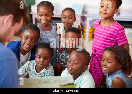 Teacher reading book to elementary school children in class Stock Photo