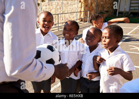 Teacher with ball and kids in elementary school playground Stock Photo