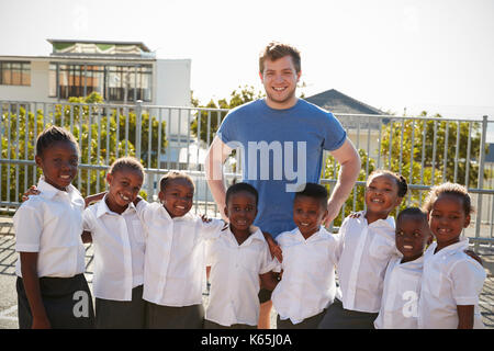 Volunteer and elementary school kids in playground, portrait Stock Photo