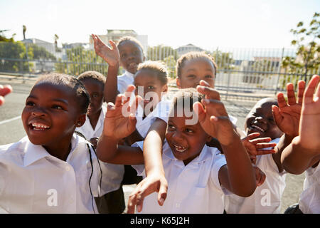 Elementary school kids in playground waving to camera Stock Photo