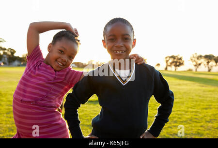 Two African elementary schoolgirls pose to camera in a field Stock Photo