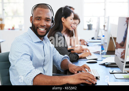 Young black man with headset on smiling to camera in office Stock Photo
