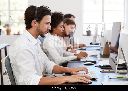 Hispanic man with headset on working at computer in office Stock Photo
