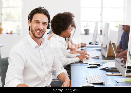 Hispanic man with headset on smiling to camera in an office Stock Photo