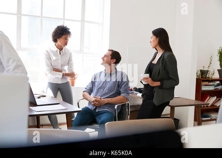 Young man and two female colleagues talking in an office Stock Photo