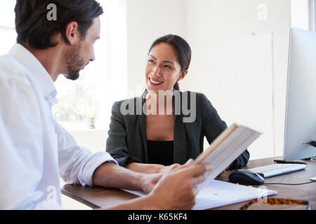 Man and woman with documents in an office, smiling, close up Stock Photo