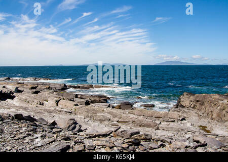 Landscape shot of the coast line at Cromwell Point,Valentia Island, Ring of Kerry, Ireland on a bright sunny day against a blue sky with cirrus clouds Stock Photo