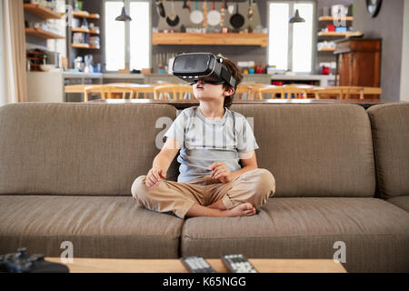 Boy Sitting On Sofa Wearing Virtual Reality Headset Stock Photo