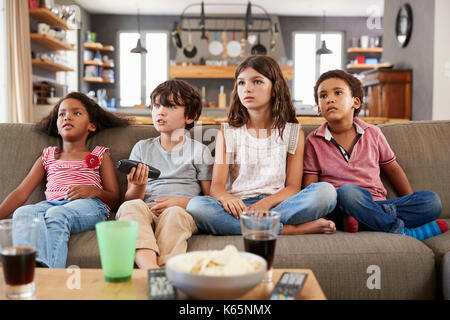 Group Of Children Sitting On Sofa Watching Television Together Stock Photo