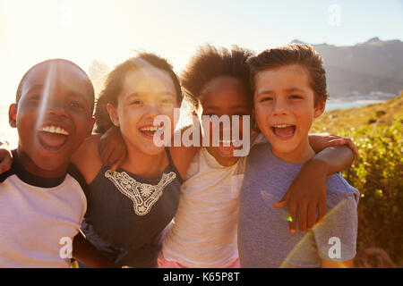 Portrait Of Smiling Children Standing On Cliffs By Sea Stock Photo