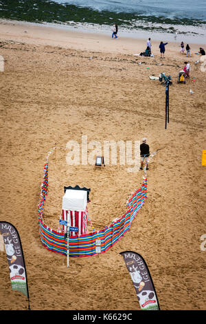 England, Broadstairs. Aerial view of lone Punch and Judy man standing by show entrance on almost deserted beach during period of overcast cold weather. Stock Photo