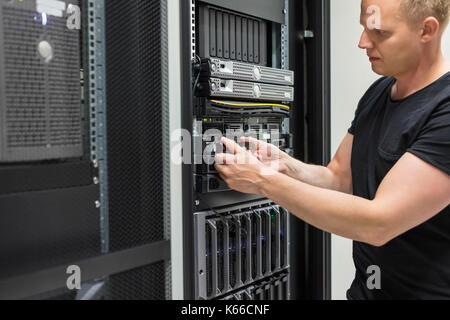 Male Technician Installing Hard Drive In Datacenter Stock Photo
