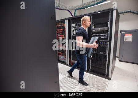 Male Technician Carrying Blade Server While Walking In Datacente Stock Photo