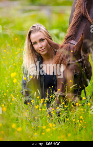 Smiling woman sits in the meadow with her arabian horse Stock Photo