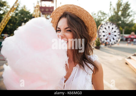 Close up portrait of a pretty young girl eating cotton candy at amusement park Stock Photo
