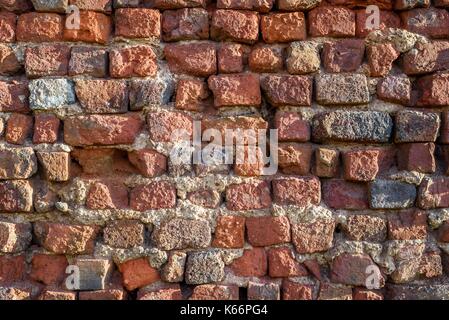 An old eroded terracotta red brick wall background. Stock Photo