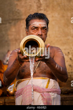 VARANASI, INDIA - CIRCA NOVEMBER 2016: Man worshiping in the Ganges river in Varanasi. Varanasi is the spiritual capital of India, the holiest of the  Stock Photo