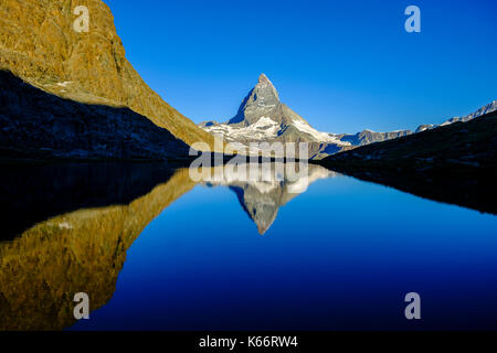 The East Face of the Matterhorn, Monte Cervino, mirroring in the Lake Riffelsee at sunrise Stock Photo