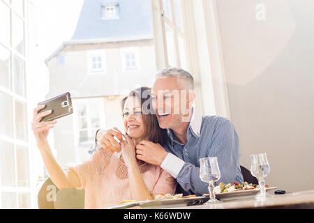 Caucasian couple posing for cell phones selfie in restaurants Stock Photo