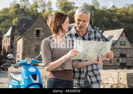 Caucasian couple near blue motor scooter reading map Stock Photo