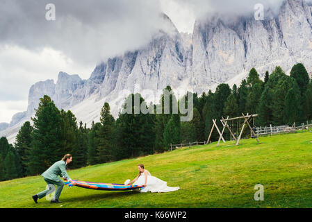 Bridge and groom walk in the meadow of Alto Adige / South Tyrol with stunning Dolomites mountain range in the background Stock Photo