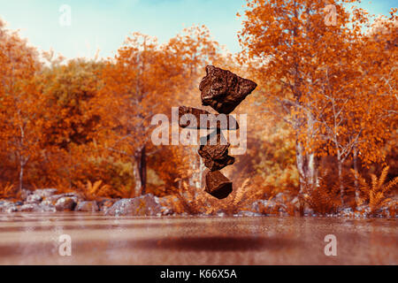 Stack of balancing rocks hovering mid-air in autumn Stock Photo