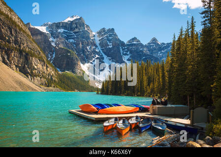 Canoes on a jetty at  Moraine lake in Banff National Park, Alberta, Canada, with snow-covered peaks of canadian Rocky Mountains in the background. Stock Photo