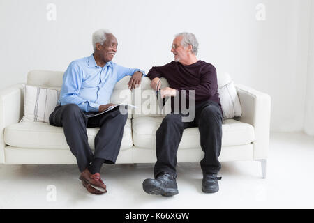 Older men reading magazines sitting on sofa Stock Photo