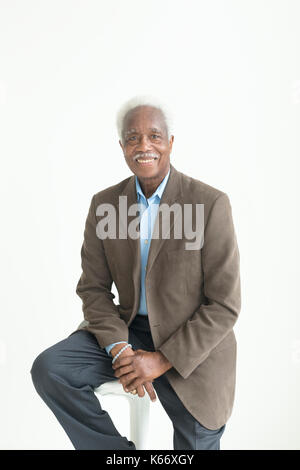 Portrait of older smiling Black man sitting on stool Stock Photo
