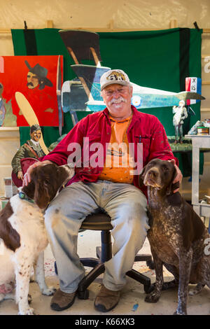 Portrait of older Caucasian man sitting in workshop with dogs Stock Photo