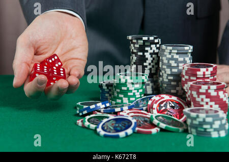 Hand holding three red dice on a green casino table Stock Photo