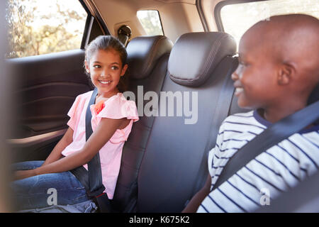 Smiling girl and boy looking at each other in car on a trip Stock Photo
