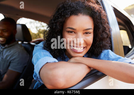 Young black woman looking out of car window smiles to camera Stock Photo