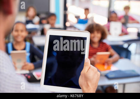 Teacher holding tablet in school class, over shoulder view Stock Photo
