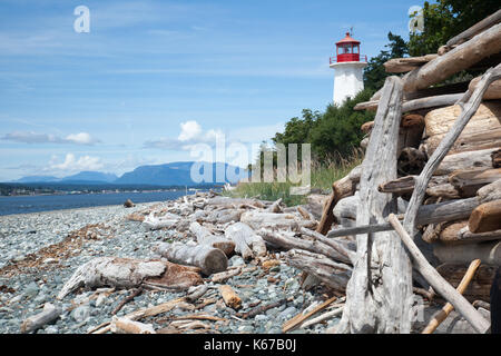 Driftwood and lighthouse on beach, Quadra Island, Columbia, Canada Stock Photo