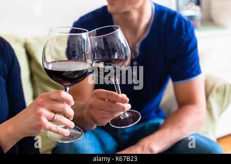 Romantic young couple toasting with red wine while sitting on th Stock Photo