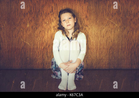 Girl hugging her knees on floor Stock Photo - Alamy