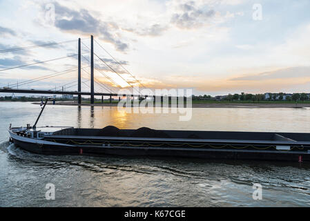 Cargo ship loaded with tons of coal sailing on the Rhine River at dusk in Dusseldorf, Germany Stock Photo