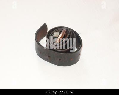 a coiled up black metal belt on the bed; England; UK Stock Photo