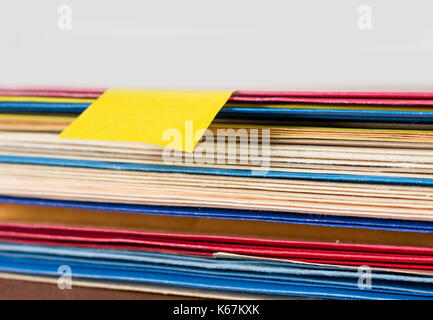 a blank sticky note sits on a pile of colored work documents Stock Photo