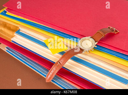 stack of papers with a watch and to do sticky note, a well organized work area with to do tasks Stock Photo