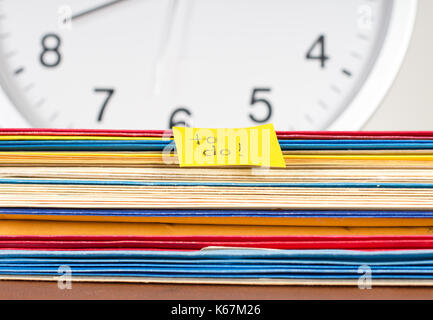 a stack of work papers with a clock and to do note signify a deadline Stock Photo
