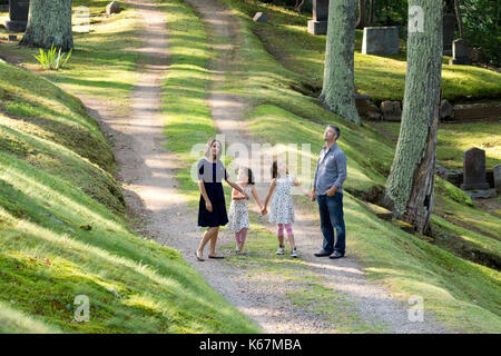 parents holding hands with two daughters walking and exploring on a path looking around Stock Photo