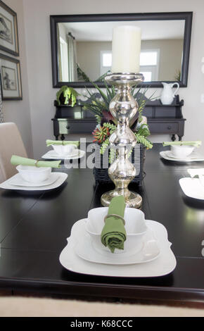 Looking down a brown dining room table at place settings with bowls an green napkins laid out. Stock Photo