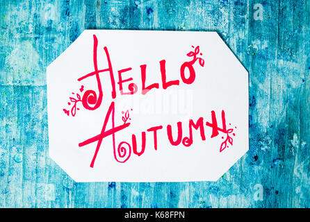 Hello Autumn calligraphy note with fallen leaves on blue board Stock Photo