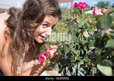 Young woman with long light brown hair  looking up as she holds roses Stock Photo