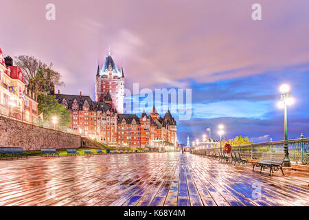 Quebec City, Canada - May 30, 2017: Closeup of old town ground level view of wet dufferin terrace boardwalk at night with Chateau Frontenac, purple cl Stock Photo