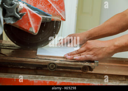 Manual cutting of ceramic tiles on a special machine for cutting tiles. Background blur Stock Photo