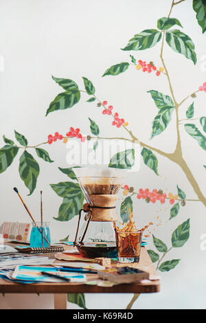 Brewing coffee in chemex with a dynamic coffee splash and still life with watercolor and artist tools. Alternative coffee brewing method. Professional Stock Photo