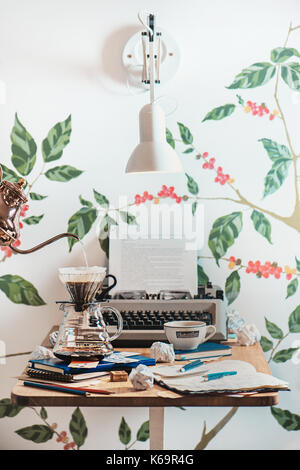 Writer workplace in a cafe with a typewriter, drafts, crumpled paper and coffee prepared with a cone-shaped pour over filter. Alternative coffee brewi Stock Photo